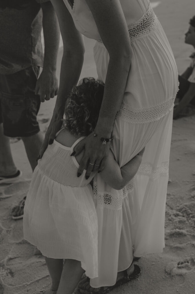 Toddler hugging mom on pensacola beach during family pictures